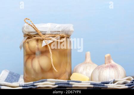 Marinierter Knoblauch im geschlossenen Glas und frisch auf Holz Tabelle gesunde fermentierte Lebensmittel hausgemachte Gurken Stockfoto