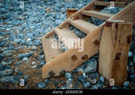 Verwitterte Holztreppen führen seitwärts von einem Kiesstrand in Norfolk, Großbritannien Stockfoto