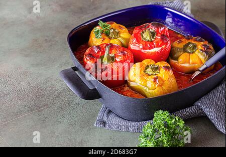 Gebackene gefüllte Paprika mit Huhn oder truthahn, Mais und Kräuter in tiefem Gericht, grüner Hintergrund. Stockfoto