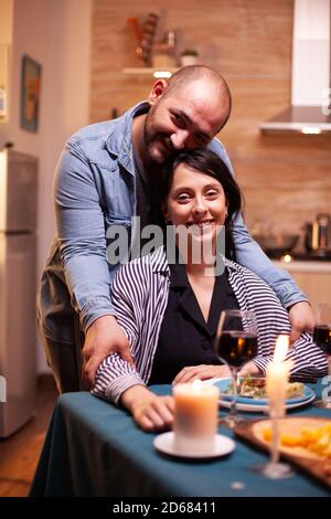 Romantisches Paar mit Blick auf Webcam während romantischen Abendessen. Verheiratete Menschen besondere zärtliche Momente, genießen das Essen bei Kerzenschein Feier. Stockfoto