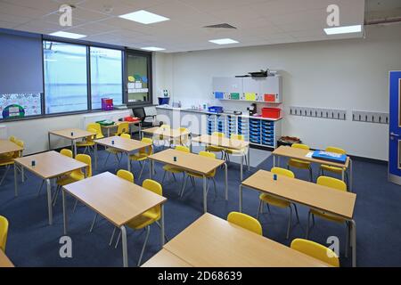 Neu gebautes Schulzimmer mit zwei Schreibtischen, die nach vorne zeigen. Ein traditionelles Layout, das während der Covid-Pandemie von 2020 wieder eingeführt wurde. Stockfoto