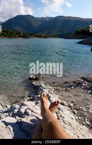 Weibliche Beine entspannen in atemberaubenden Fiastra Lake.Urlaub und lokale Reisen Concepts.Young Frau verbringt Zeit allein in nature.menthal ad körperliches Wohlbefinden Stockfoto