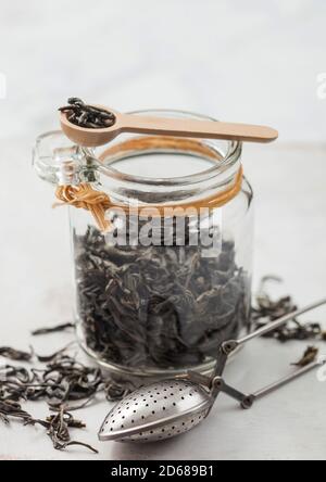 Glas Glas von organischen losen grünen Tee mit Vintage-Metall-Sieb Infuser auf hellen Tisch Hintergrund. Stockfoto