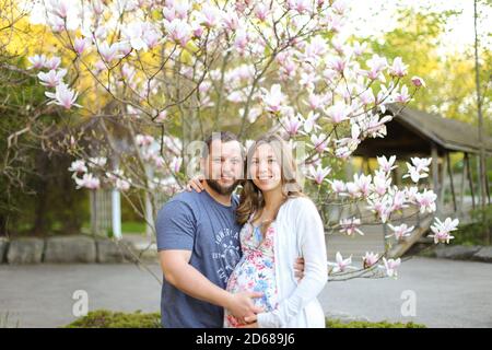 Glücklich Mann umarmt schwangere Frau draußen. Stockfoto