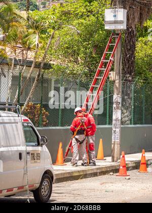 MEDELLIN, KOLUMBIEN - 12. Okt 2020: Medellin, Antioquia / Kolumbien - 11 2020. Oktober: Zwei Elektrotechniker in roten Uniformen bereiten sich auf einen Red vor Stockfoto