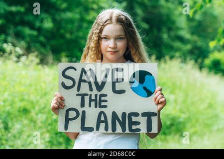 kaukasische blonde Mädchen Aktivist mit retten den Planeten Poster im Park. Preteen Kind Freiwilligen gegen Verschmutzung, globale Erwärmung, Müll zu recyceln. Ökologie Stockfoto