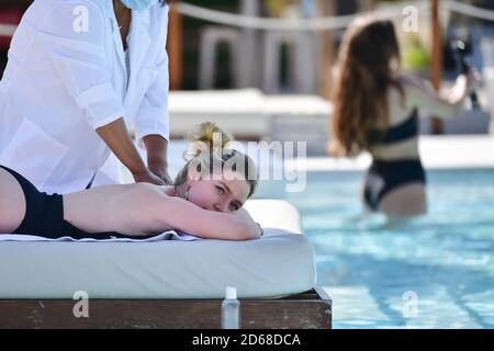 Nahaufnahme einer blonden Frau, die den Bauch nach unten legt und eine Massage mit einer unfokussieren Frau auf dem Rücken erhält. Freizeit- und Wohlbefindungs-Konzept. Stockfoto