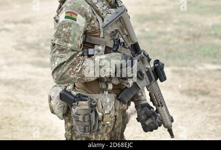 Soldat mit Sturmgewehr und Flagge Boliviens auf Militäruniform. Collage. Stockfoto