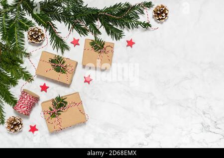 Kunststoff frei Weihnachten flach legen mit handgefertigten geschenkboxen, Nadelbaum Äste, Tannenzapfen, Holzsterne auf Marmor Hintergrund. Grußkarte Stockfoto