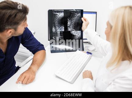 Der Neurologe betrachtet und diskutiert mit dem Patienten ein Röntgenbild seiner Halswirbelsäule. Diagnostik und Behandlung der zervikalen Osteochondrose von sp Stockfoto