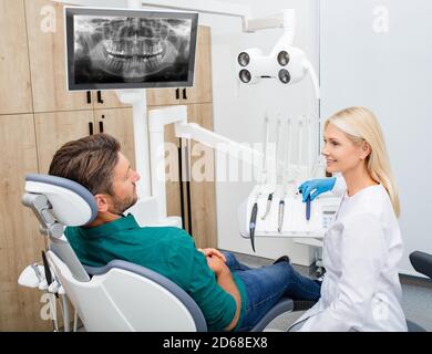 Schöne Frau Zahnarzt Beratung eines Mannes Patienten in der Zahnarztpraxis. Stomatologie und Gesundheitskonzept Stockfoto