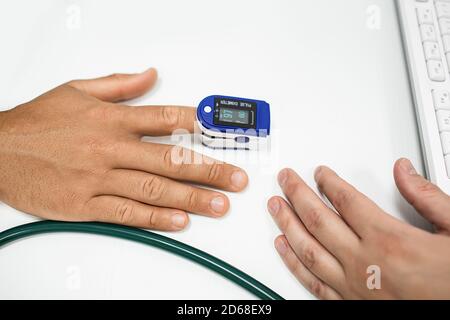 Pulsoximeter Messung von Pulsfrequenz und Sauerstoff, bei Nahaufnahme des männlichen Fingers Stockfoto