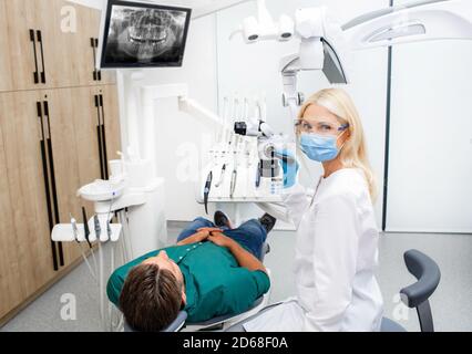 Porträt einer schönen Zahnärztin in Schutzbrille und Eine Maske während der Behandlung eines Patienten in einer Zahnarztpraxis Stockfoto