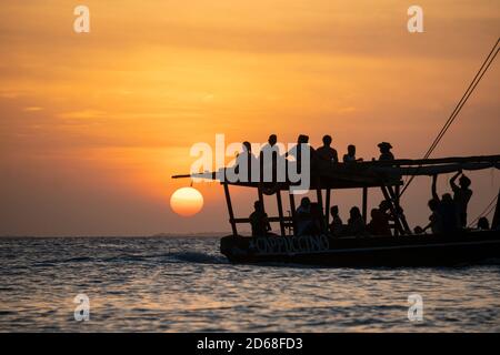 Dhow Segeln während Sonnenuntergang in Sansibar. Dhow ist ein Holzschiff mit einem Segel, das zum Transport von Gütern verwendet wird. Hauptsächlich im Indischen Ozean verwendet Stockfoto