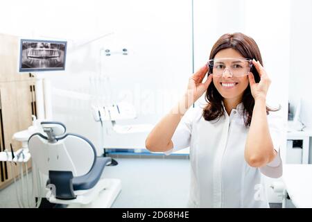 Portrait Zahnärztin trägt eine Schutzbrille und steht in ihrer Klinik. Stockfoto