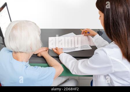 Der Kardiologe befragt eine ältere Frau zu den Ergebnissen eines Elektrokardiogramms. Herzinfarkt, Testergebnisse Stockfoto