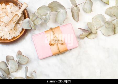 Ein rosa Seifenstück mit Eukalyptuszweigen auf Marmor Tabelle in einer Draufsicht Stockfoto