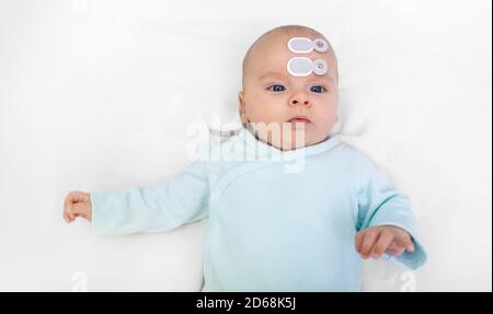 Hörscreening für Neugeborene und Diagnose im Krankenhaus. Baby mit Hörscreening mit speziellen Elektroden an Kopf und Ohr Stockfoto