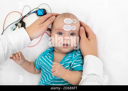 Hörscreening für Neugeborene und Diagnose im Krankenhaus. Baby mit Hörscreening mit speziellen Elektroden an Kopf und Ohr Stockfoto