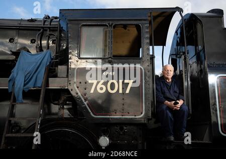 Fahrer Dave Pallett, Wer sich seit über 25 Jahren freiwillig für die Mid Hants Railway engagiert, schaut aus dem Fahrerhaus der British Railways Standard Class 4MT Dampflokomotive 76017, während er vor der Herbst-Dampfgala auf der Watercress Line der Mid Hants Railway für ein Foto am Bahnhof Ropley posiert. Stockfoto