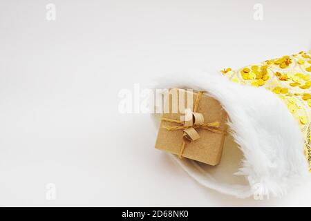 Geschenkschachtel in Kraftpapier verpackt und gebunden Sackleinen In gelber weihnachtssocke auf weißem Hintergrund Stockfoto