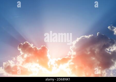 Sonnenuntergangsstrahlen hinter den Wolken und Schatten am blauen Himmel, kopieren Raum. Stockfoto