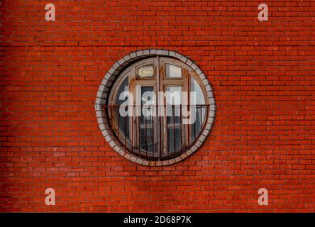 Vintage Kreis Holzfenster auf einem Backsteinmauer Gebäude. Architektonische Gestaltung mit Linien und Kreis Stockfoto