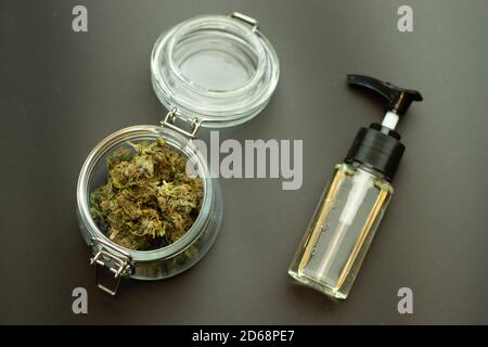 CBD Kräuteröl mit Cannabisknospen in Glasglas Draufsicht. Marihuana auf schwarzem Hintergrund. Weed Business Branchenkonzept. Cannabidiol medizinische und Stockfoto