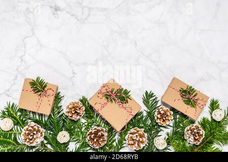 Kunststoff frei Weihnachten flach legen mit Nadelbaum Äste, Tannenzapfen und handgefertigten geschenkboxen auf Marmor Hintergrund. Grußkarte, Platz für Text kopieren Stockfoto
