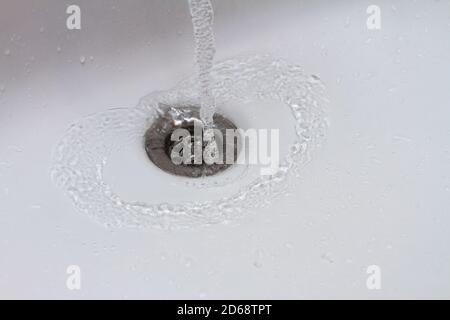 Wasser läuft in der Nähe in den Abfluss, Tropfen Wasser fällt in Zeitlupe Stockfoto