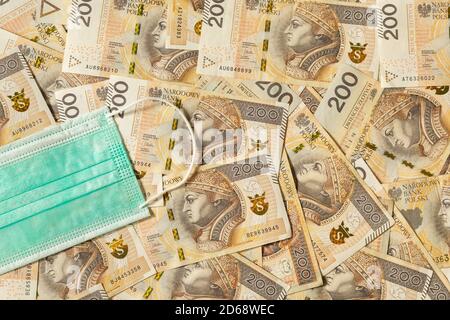 Viele 200 Zloty Scheine mit einer medizinischen Schutzmaske auf ihnen. Konzeptionelles Bild über die Stabilität der Wirtschaft in Polen. Stockfoto