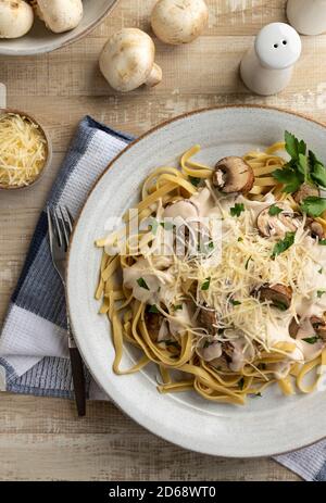 Cremige Fettuccine alfredo mit Pilzen und zerfetztem Parmesan auf einem Teller. Overhead-Ansicht Stockfoto