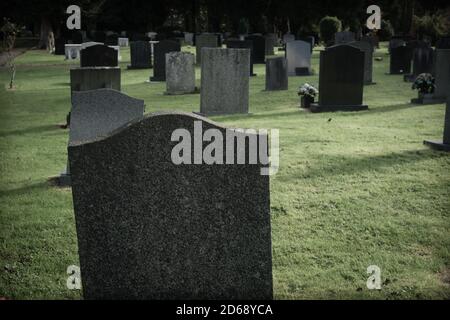 Leere Grabsteine oder Markierungen auf einem Friedhof mit einem Dunkler und düsterer Filter, der auf das Bild angewendet wird Stockfoto