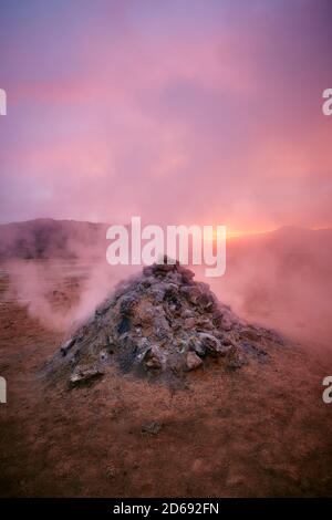 Dampfentlüftung aus einer aktiven Fumarole / Fumerole im Geothermiegebiet von Namafjall / Hverir in der Nähe des Myvatn-Sees in der Dämmerung in Nordisland. Stockfoto