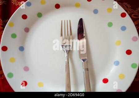 Sauberes Besteck, mit Blick auf ein Messer und eine Gabel auf weißen Keramikplatten. Stockfoto