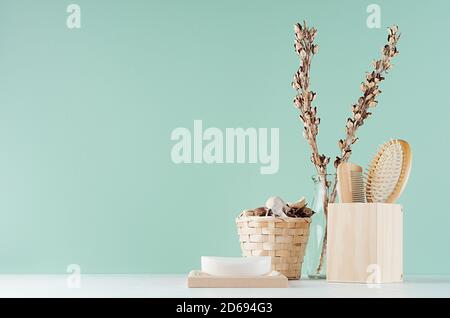 Badausstattung mit beige Bio-Kosmetik und Zubehör für die Hautreinigung und getrocknete Blumen - Kamm, Seife auf weißem Holz, Minze menthe. Stockfoto