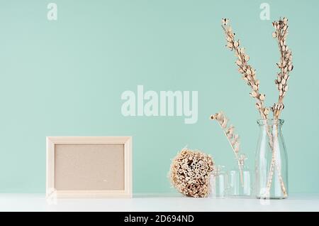Home Dekorationen im Öko-Stil - beige Holzrohlrahmen, getrocknete Pflanzenbündel und Blumen in Glasvase in grüner Minze menthe Interieur auf weißem Holz Wildschwein Stockfoto