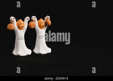 Zwei lustige essbare Zuckergeister mit Kürbissen auf schwarzem Hintergrund. Festliche Halloween Leckereien.Halloween Party Einladung, Postkarte. Stockfoto