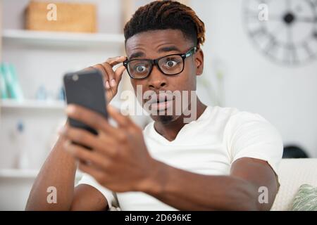 Schockierter Mann in einer Brille überrascht von Smartphone-Inhalt Stockfoto