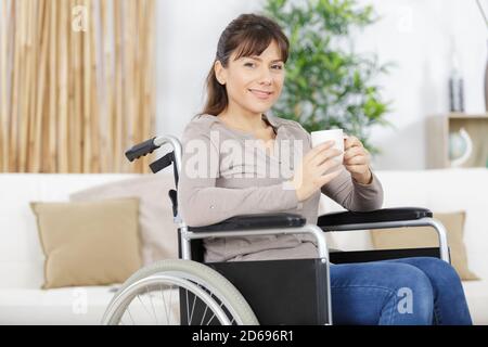 Behinderte Person im Rollstuhl mit einem Kaffee zu Hause Stockfoto
