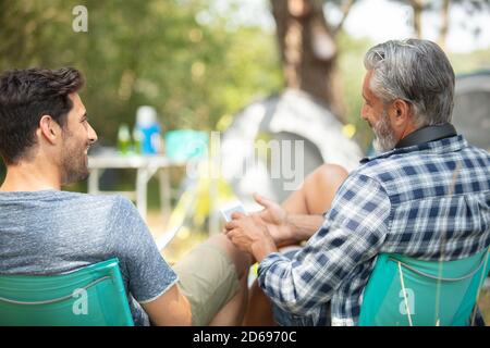 Zwei Männer sitzen auf einem weichen Stuhl auf dem Campingplatz Stockfoto