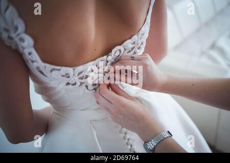 Nahaufnahme einer Frau, die ein Hochzeitskleid fixiert Stockfoto