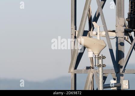 Nahaufnahme eines drehenden Anemometers zur Messung der windgeschwindigkeit, montiert auf Stahlturm. Windmessung, Wetter- und Technologiekonzepte Stockfoto