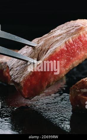 Carving Gabel mit Stücken von Wagyu Steak Nahaufnahme auf ein Schiefer Stockfoto