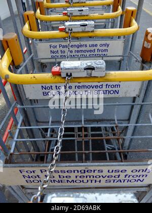 Zusammengekettete Gepäckwagen warten darauf, dass Passagiere eine £1-Münze zum Entsperren verwenden und sie auf Plattform 1 am Bournemouth Central Station verwenden. 23. Juli 2014. Foto: Neil Turner Stockfoto