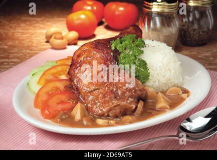 Geschmorte Hähnchenschenkel mit Gemüse, Pilzsauce und Reis Stockfoto