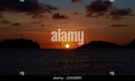 Schöner Sonnenuntergang am tropischen Strand Port Launay im Norden von Mahe, Seychellen mit hellgelber Sonne über dem Horizont des Ozeans. Stockfoto