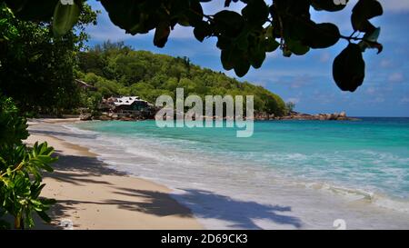 Tropischer Strand Anse Takamaka an der Westküste von Mahe, Seychellen mit türkisfarbenem Wasser, Regenwald und luxuriösem Ferienort. Stockfoto