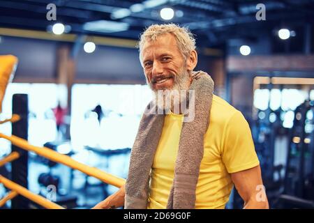 Ruhe nach dem Boxtraining. Porträt eines positiven schönen reifen Mann in Sportkleidung Blick auf Kamera und lächelnd, während auf dem Ring zu stehen Stockfoto