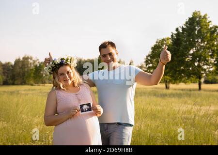 Junge Eltern freuen sich in der Schwangerschaft. Ein Ehepaar hält eine Ultraschalluntersuchung, die ihr Kind zeigt. Stockfoto